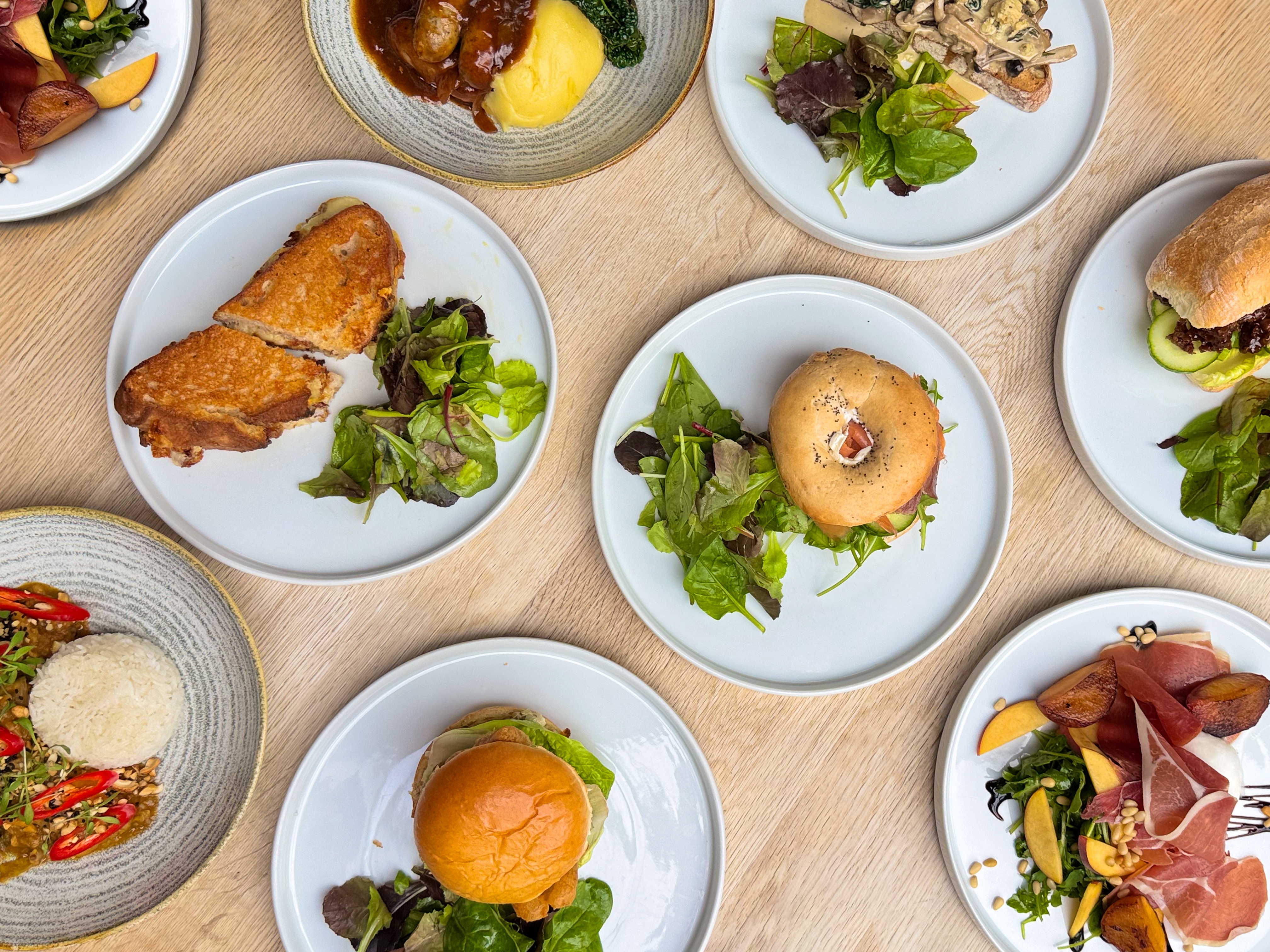 Selection of new menu items from the autumn 2025 menu - including peach and burrata salad, duck ciapanini, garlic mushrooms on toast, smoked salmon and cream cheese bagel, fish finger sandwich, grilled cheese, Malaysian curry, sausages and mash